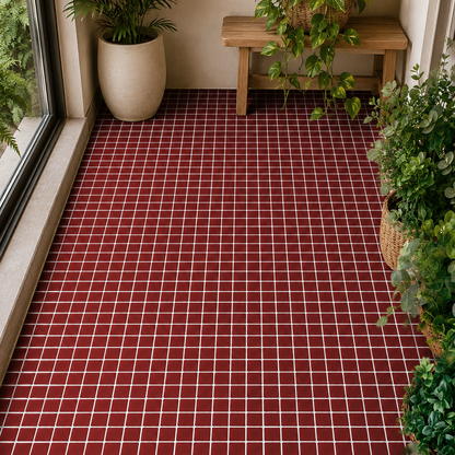 Red and white checkered tile flooring installed in a sunlit indoor balcony or patio area surrounded by potted green plants and a wooden bench.